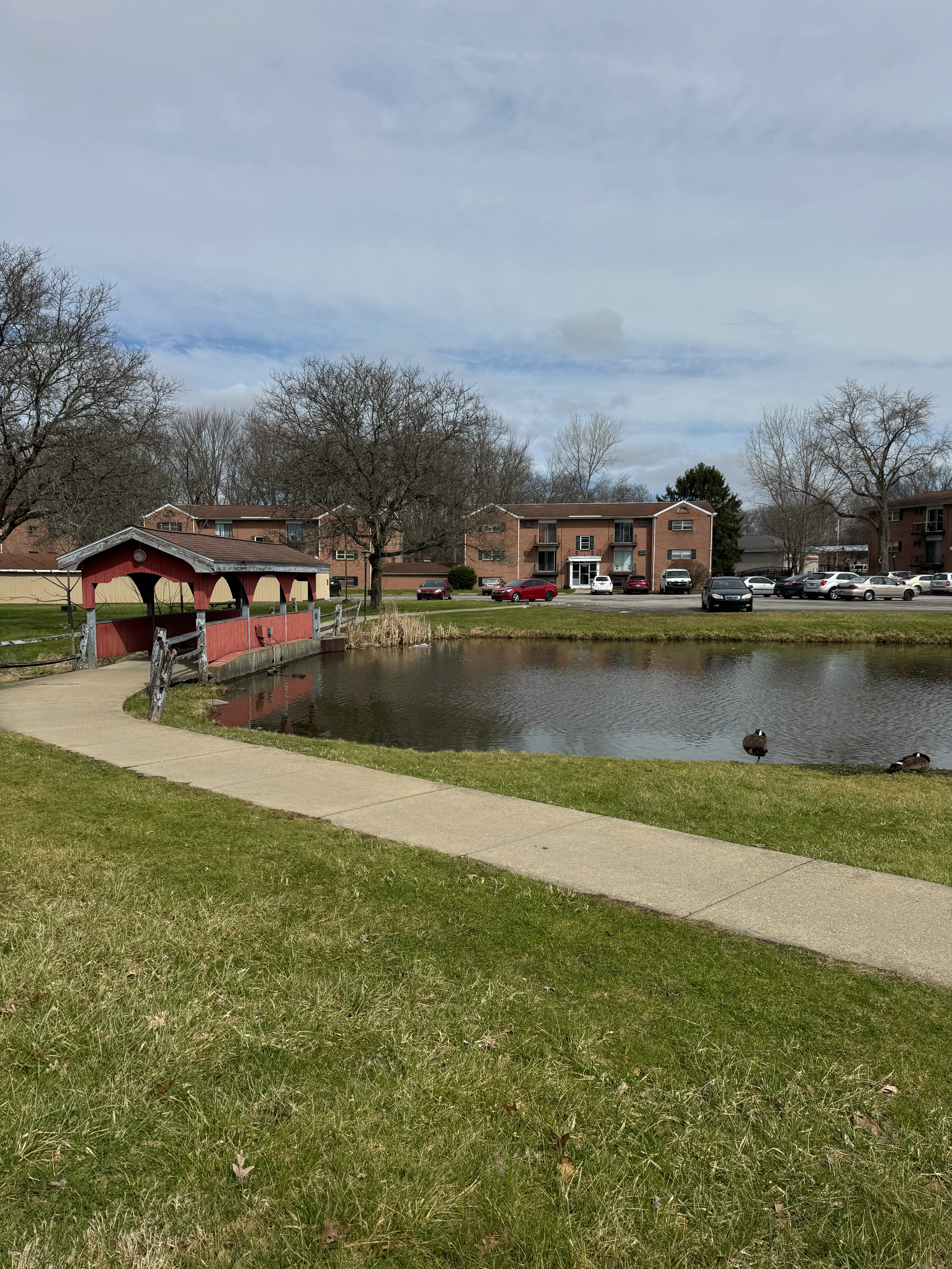 Close view of the red covered footbridge over the pond.